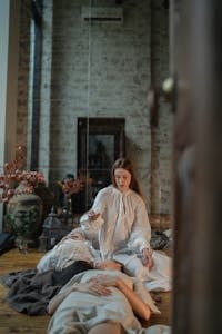 A woman performs a healing ritual indoors with candles and crystal arrangements.