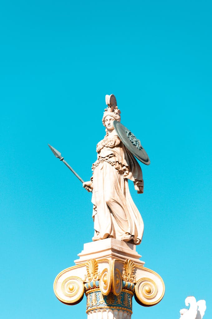 Elegant Greek statue of Athena in Athens against a vivid blue sky, showcasing classical artistry.