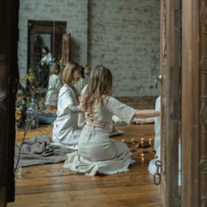 Group of women engaged in spiritual ritual in serene indoor setting with candles.
