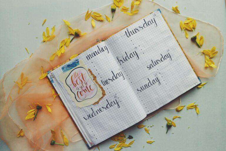 Open planner with days of the week, surrounded by yellow petals and an inspiring quote.