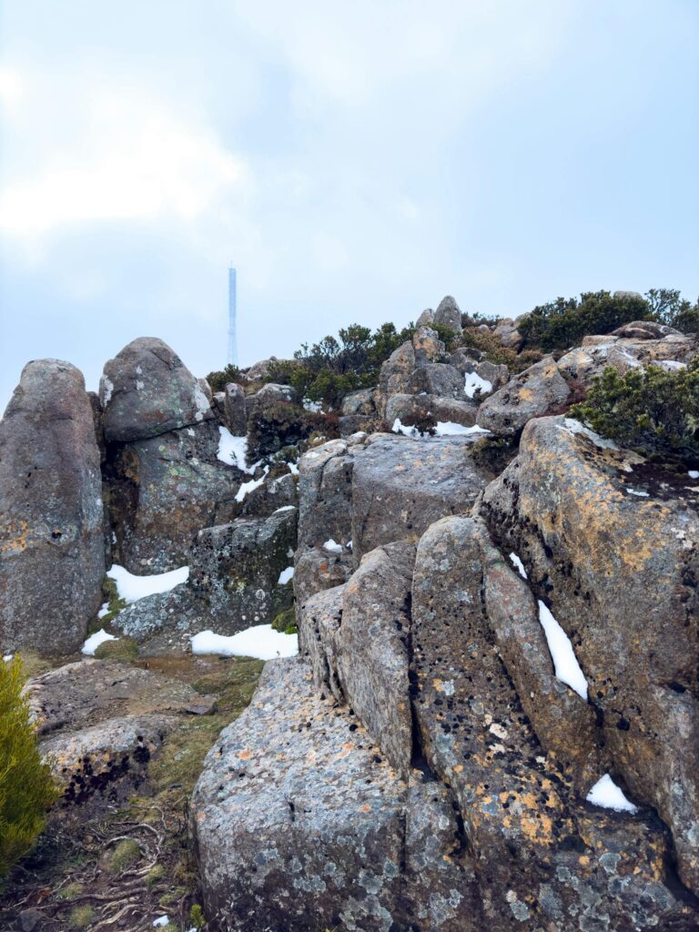 A scenic view of rugged rocks with patches of snow highlights the winter landscape.