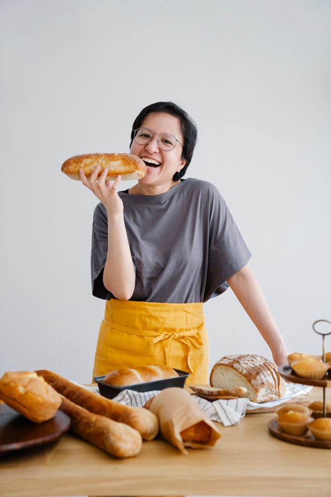Happy baker showcasing a fresh loaf of bread in a cozy kitchen setting.