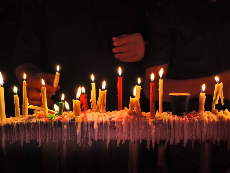 Close-up of colorful lit candles on a dark background, creating a warm ambiance.